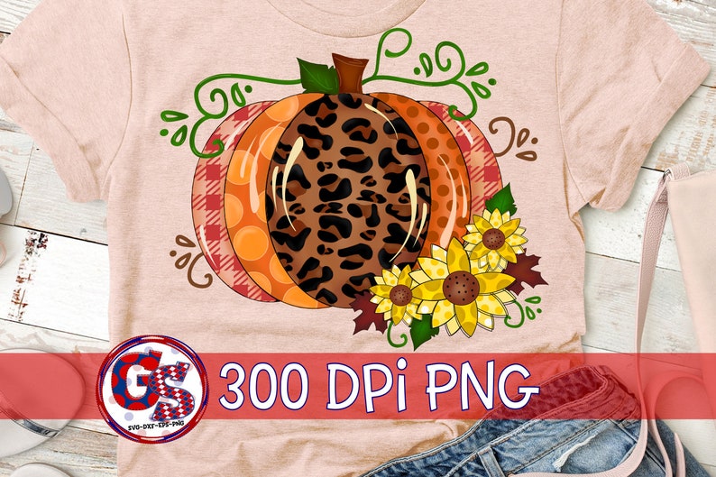 Puede incluir: Camiseta color melocot&oacute;n con un dise&ntilde;o de calabaza grande y colorido. La calabaza tiene secciones de estampado de leopardo, lunares naranjas y cuadros rojos. Los girasoles y las vides verdes acent&uacute;an la calabaza. Tambi&eacute;n se ve el texto "300 DPI PNG".
