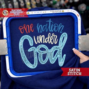 May include: A navy blue fabric with the embroidered phrase "one nation under God" in red, white, and light blue glitter. The fabric is held in a blue embroidery hoop. The words "SATIN STITCH" are in a red banner.
