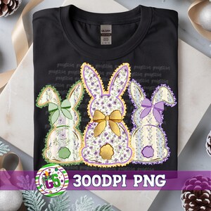 May include: Black t-shirt featuring three Easter bunny designs. Each bunny has a floral pattern in pastel colors, with a decorative bow. The shirt has the text "greedy stitches" repeated across the top and a logo at the bottom.