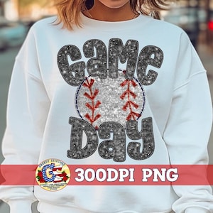 May include: White sweatshirt with a glittery black and silver design that says "Game Day" with a baseball in the middle.