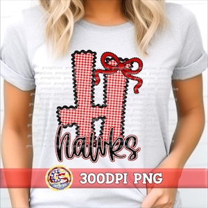 May include: A light gray t-shirt featuring a large, red and white gingham patterned letter H with a black scalloped border. A red bow with a black outline sits atop the letter. The word hawks is written below in black script with a red outline.