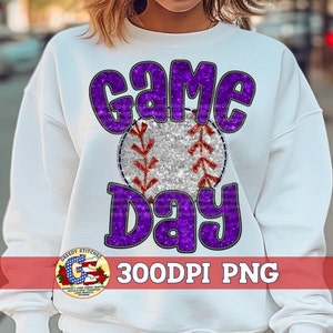 May include: White sweatshirt with a purple and silver glitter design that says "Game Day" with a baseball in the middle.