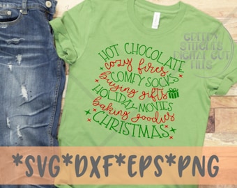 May include: A light green t-shirt with a festive design. The shirt features the words "Hot Chocolate, Cozy Fires, Comfy Socks, Buying Gifts, Holiday Movies, Baking Goodies, Christmas" in red and green. The bottom of the shirt has the text "SVG DXF EPS PNG".