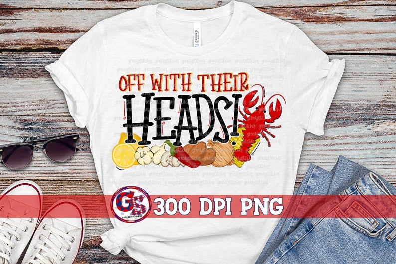 Op de afbeelding: Wit T-shirt met de tekst "Off with their heads!" in zwarte letters. Het ontwerp bevat een rode kreeft, citroenen, uien, knoflook en paprika's.