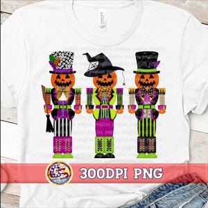 May include: White t-shirt featuring three Halloween-themed nutcracker designs. Each nutcracker has a jack-o'-lantern head, wearing a different hat and outfit. The text "300DPI PNG" is displayed on a red banner at the bottom.