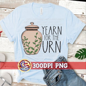 Op de afbeelding: Een lichtblauw T-shirt met een afbeelding van een bruine urn met groene wijnstokken en de tekst "Yearn for the Urn". De afbeelding is een 300 DPI PNG-bestand.