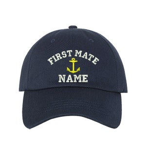 May include: A navy blue baseball cap with white embroidery that reads "First Mate" with an anchor and the word "NAME" underneath.