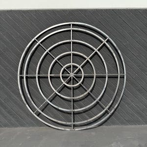 May include: A large, circular metal frame with concentric circles and radiating spokes. The frame is made of silver metal and has a slightly distressed finish.