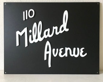 Könnte beinhalten: Schwarzes Metallschild mit weißer Aufschrift "110 Millard Avenue".