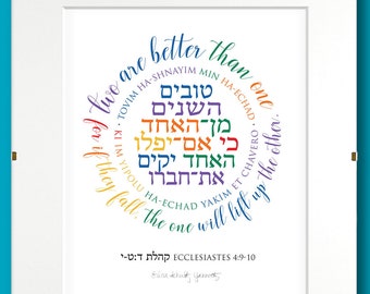 May include: A white framed print with a colorful Hebrew text design in a circle. The text reads "Two are better than one... for if they fall, the one will lift up the other."  The text is from Ecclesiastes 4:9-10.