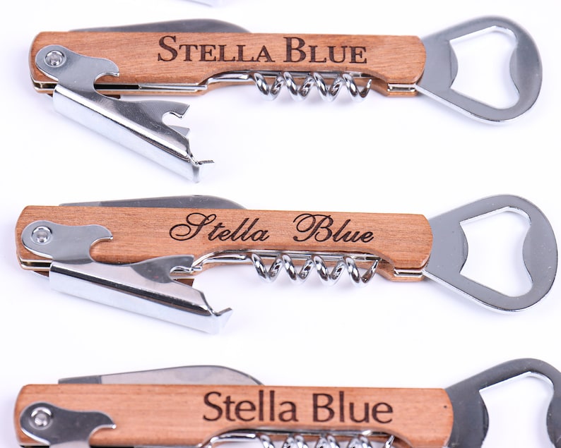 Puede incluir: Un abridor de botellas de madera con un sacacorchos y un abridor de botellas. El mango est&aacute; grabado con el nombre "Stella Blue".