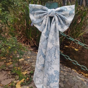 Peut inclure: Un grand nœud blanc avec un motif bleu et blanc. Le nœud est noué autour d'un poteau en bois et pend.