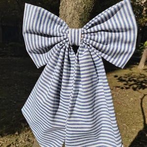 Peut inclure: Un grand nœud bleu et blanc à rayures noué autour d'un tronc d'arbre. Le nœud est en tissu et a un design simple et classique.