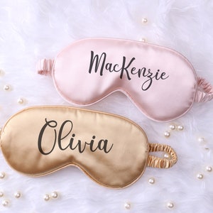 May include: Two personalized sleep masks, one pink with the name "Mackenzie" and one gold with the name "Olivia".