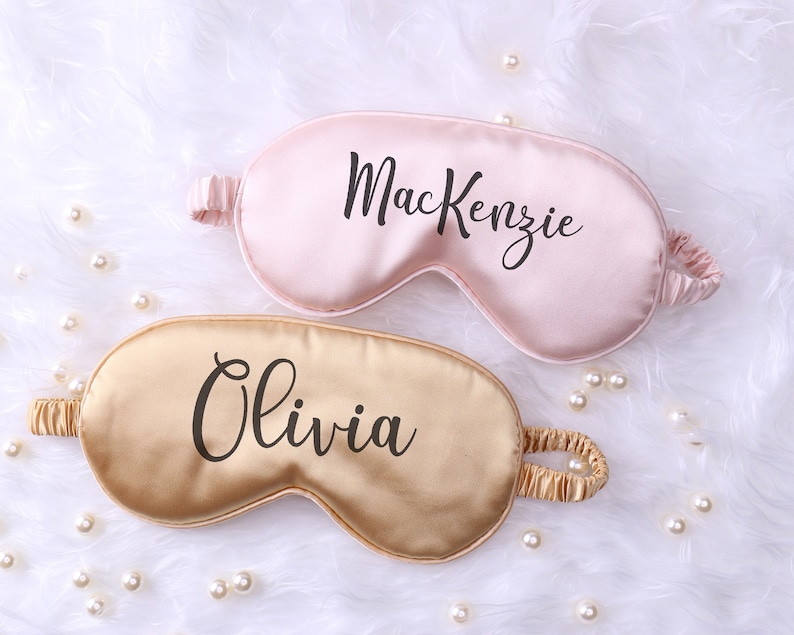May include: Two personalized sleep masks, one pink with the name "Mackenzie" and one gold with the name "Olivia".