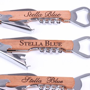 Puede incluir: Tres abridores de botellas de madera con sacacorchos y abridor de botellas. Cada abridor tiene el texto "Stella Blue" grabado en el mango.