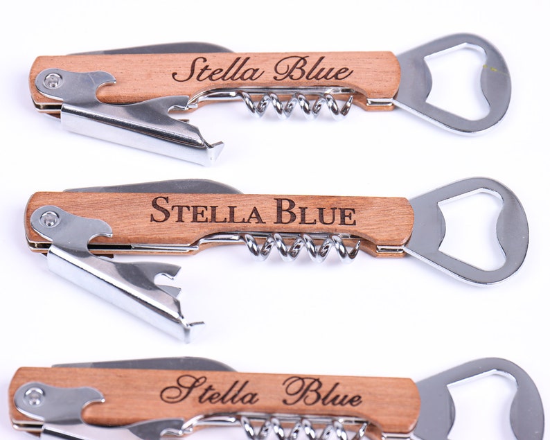 Puede incluir: Tres abridores de botellas de madera con sacacorchos y abridor de botellas. Cada abridor tiene el texto "Stella Blue" grabado en el mango.