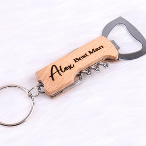 Könnte beinhalten: Ein Holzschlüsselanhänger mit einem Flaschenöffner, einem Korkenzieher und einem Schlüsselring. Der Schlüsselanhänger ist mit dem Text "Alex Best Man" graviert.