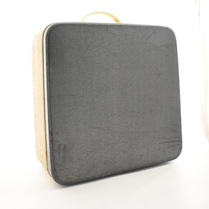 May include: A rectangular suitcase with a dark gray textured exterior and a light tan side panel. The suitcase features a rounded top handle and a silver-toned trim running along the edge of the case, providing a structured and functional design.