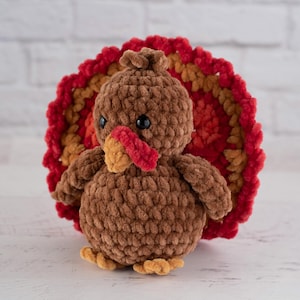 May include: A brown crocheted turkey with a red, orange, and yellow crocheted fan-shaped tail.