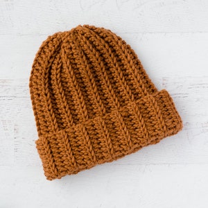 May include: A brown crocheted beanie hat with a ribbed texture.
