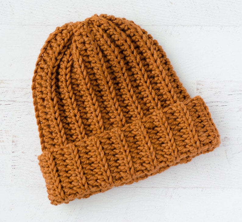 May include: A brown crocheted beanie hat with a ribbed texture.