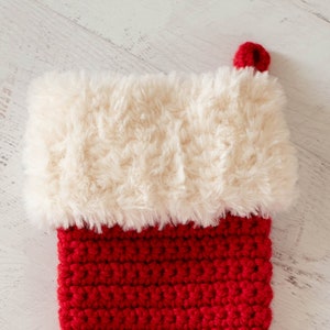 Puede incluir: Un calcet&iacute;n de Navidad de crochet rojo y blanco con un pu&ntilde;o blanco esponjoso.