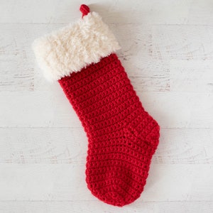 Puede incluir: Un calcet&iacute;n de Navidad rojo de ganchillo con un pu&ntilde;o de piel sint&eacute;tica blanca.