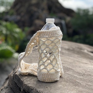 May include: White crocheted bottle cozy with a delicate openwork pattern. The cozy is designed to fit a standard water bottle.