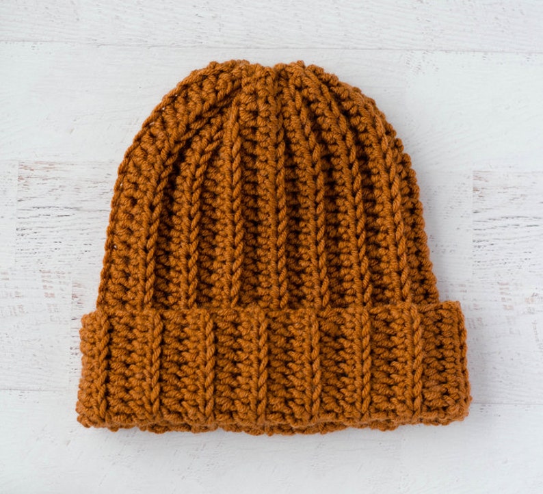 May include: A brown crocheted beanie hat with a ribbed texture.