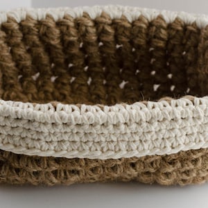 May include: A woven basket with a brown and white pattern. The basket is made of natural fibers and has a rounded shape.