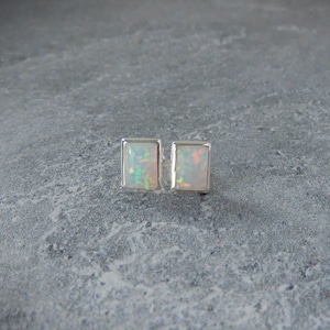 May include: A pair of silver stud earrings with rectangular white opal stones.
