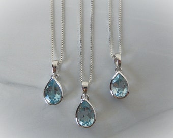 May include: Three silver necklaces with teardrop-shaped blue topaz pendants.