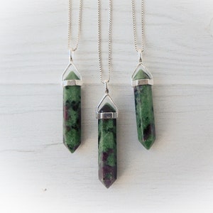 May include: Three silver chain necklaces with green and black gemstone pendants. The pendants are in the shape of a point.