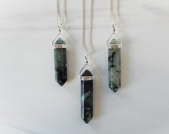 Puede incluir: Tres collares de cadena plateada con colgantes de cristal de punta verde y negro. Los colgantes tienen todos la misma forma y tamaño, pero diferentes patrones.