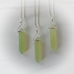 May include: Three silver necklaces with green crystal pendants. Each pendant is a pointed, faceted crystal with a silver cap at the top.