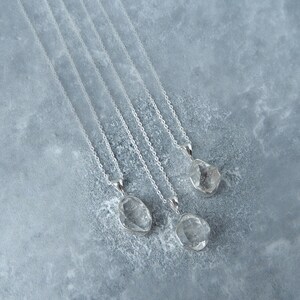 May include: Five silver necklaces with clear quartz crystal pendants. The pendants are faceted and have a rough, natural look.