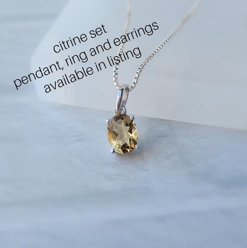 Peut inclure: Un collier en argent avec un pendentif en forme de citrine ovale de couleur brun clair. Le texte "citrine set pendant, ring and earrings available in listing" est visible sur l'image.