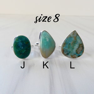May include: Three silver rings with different shaped turquoise stones. The rings are labeled J, K, and L. The text "size 8" is above the rings.