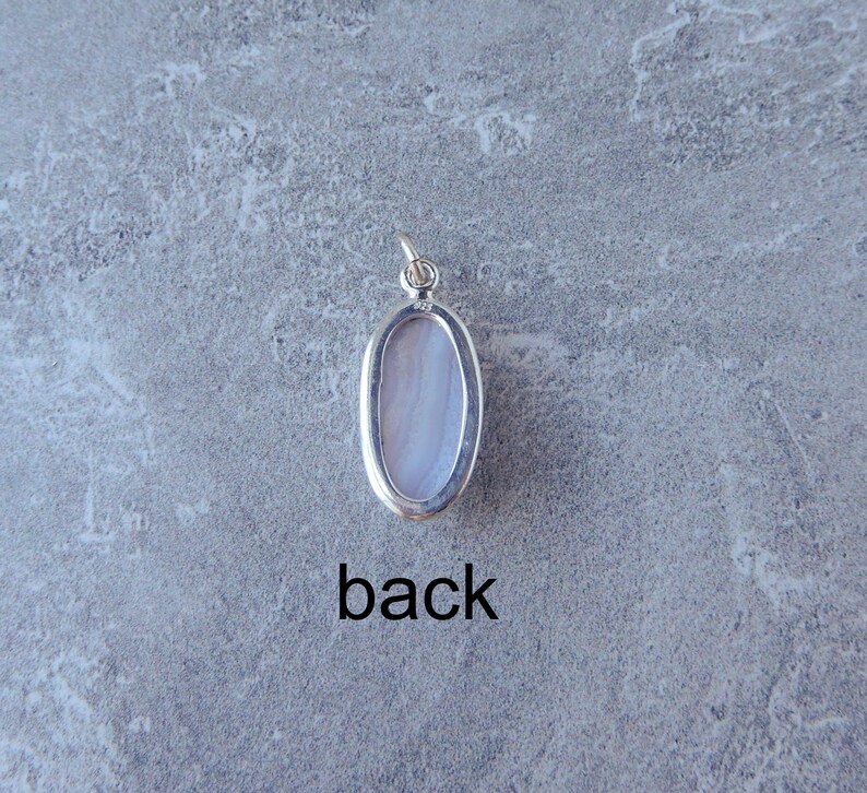 K&ouml;nnte beinhalten: Die R&uuml;ckseite eines silbernen Anh&auml;ngers mit einem hellblauen ovalen Stein. Der Anh&auml;nger hat eine &Ouml;se zum Anbringen einer Kette. Der Text "back" ist unter dem Anh&auml;nger gedruckt.
