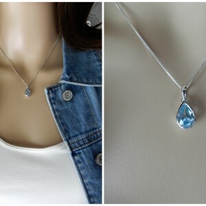 May include: A silver chain necklace with a teardrop-shaped blue topaz pendant.