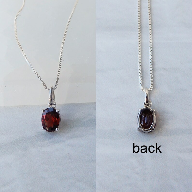 Pu&ograve; includere: Una collana a catena d'argento con un ciondolo ovale rosso. Il retro del ciondolo &egrave; visibile nella seconda immagine.