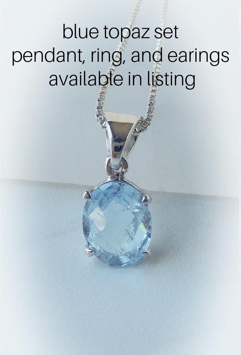 May include: A silver chain necklace with a pendant featuring a light blue topaz gemstone. The text "blue topaz set pendant, ring, and earrings available in listing" is visible above the necklace.