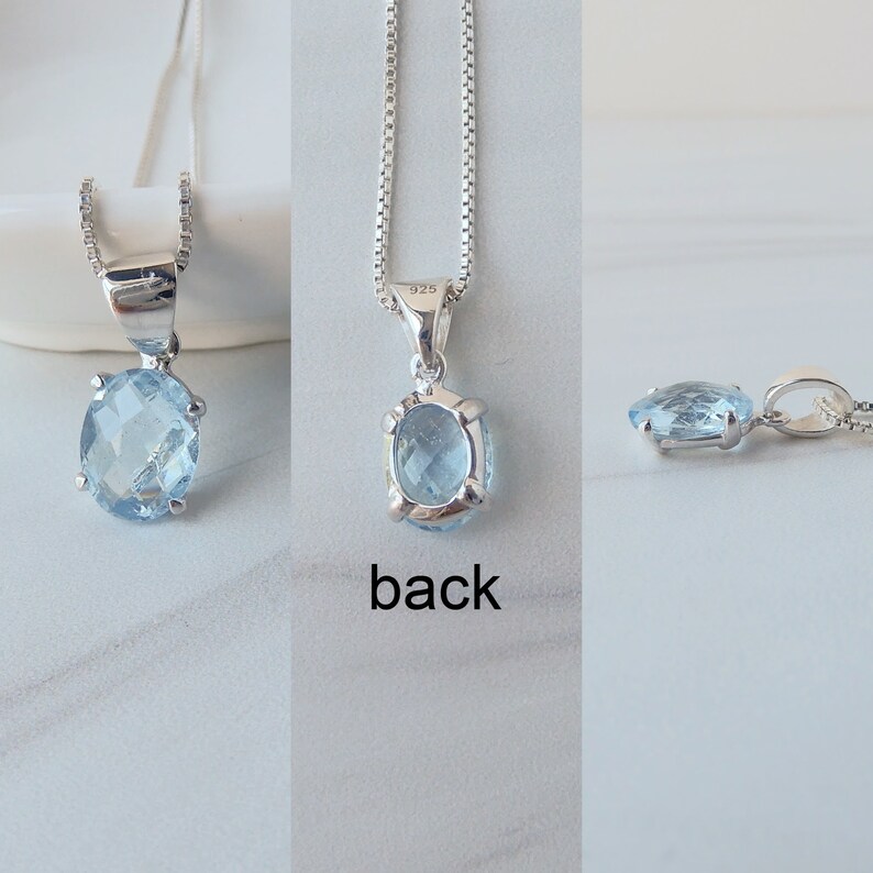 May include: A silver chain necklace with a light blue oval gemstone pendant. The pendant is set in a silver bezel and has a 925 stamp on the back.