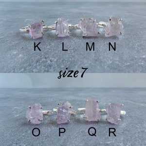 K&ouml;nnte beinhalten: Acht Silberringe mit rosafarbenen Kristallsteinen. Die Ringe sind mit K, L, M, N, O, P, Q und R beschriftet. Die Ringe sind Gr&ouml;&szlig;e 7.