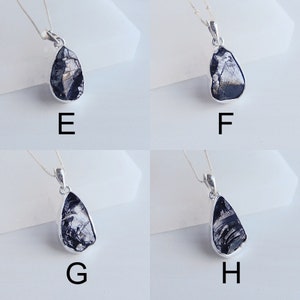 May include: Four silver necklaces with black teardrop-shaped pendants. Each pendant has a unique pattern of silver and black.
