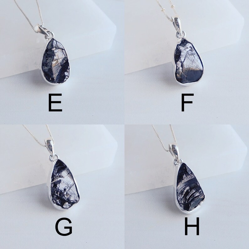 May include: Four silver necklaces with black teardrop-shaped pendants. Each pendant has a unique pattern of silver and black.