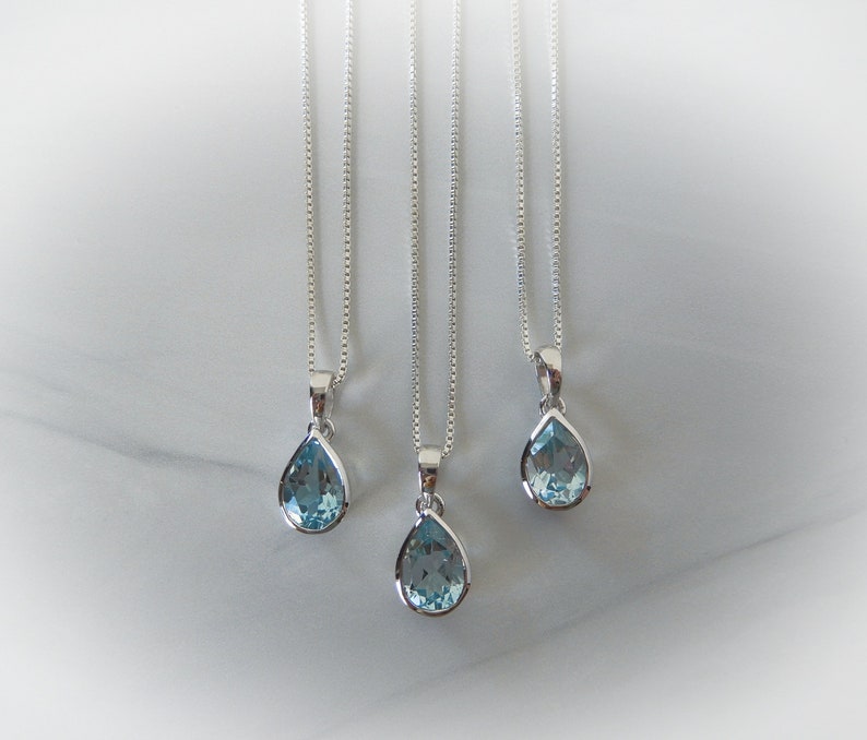May include: Three silver necklaces with teardrop-shaped blue topaz pendants.