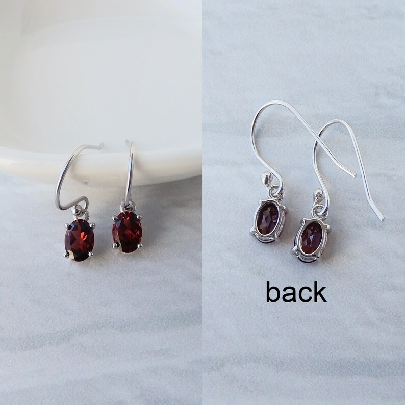 Pu&ograve; includere: Un paio di orecchini pendenti in argento con pietre preziose rosse di forma ovale. Il retro degli orecchini &egrave; mostrato nell'immagine, con la parola "back" stampata sotto.