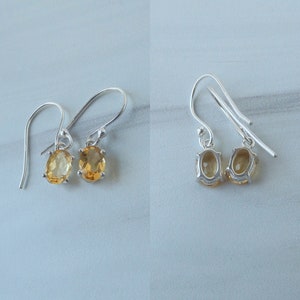 Peut inclure: Une paire de boucles d'oreilles pendantes en argent avec des pierres pr&eacute;cieuses en topaze de forme ovale. Les boucles d'oreilles ont un design simple et sont parfaites pour un usage quotidien.